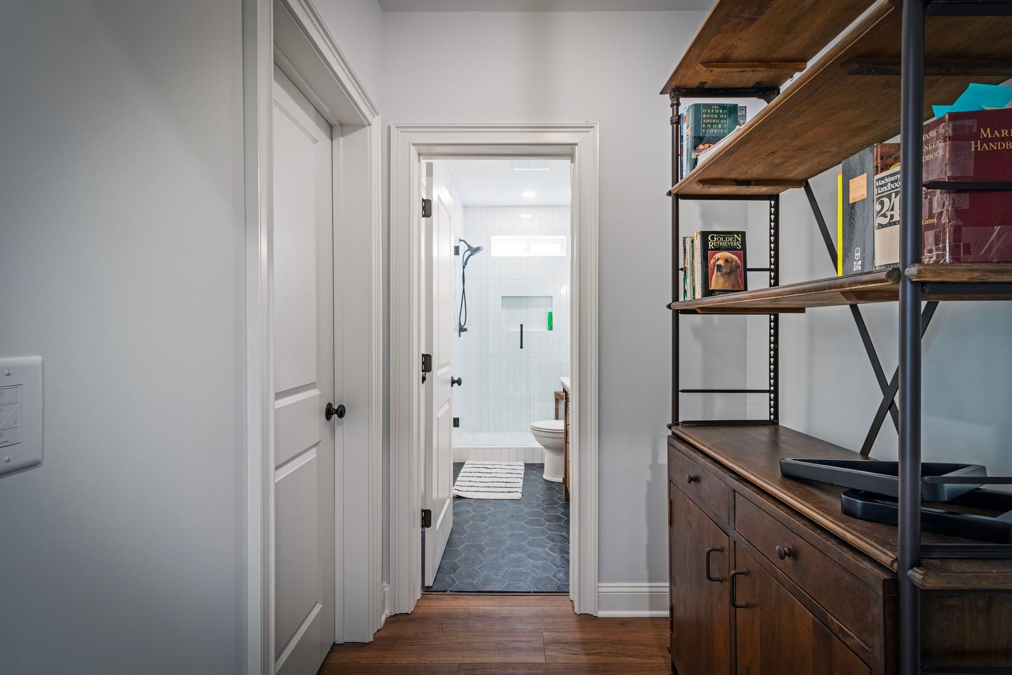 Hallway opening to a tiled walk-in shower with hex floor tile
