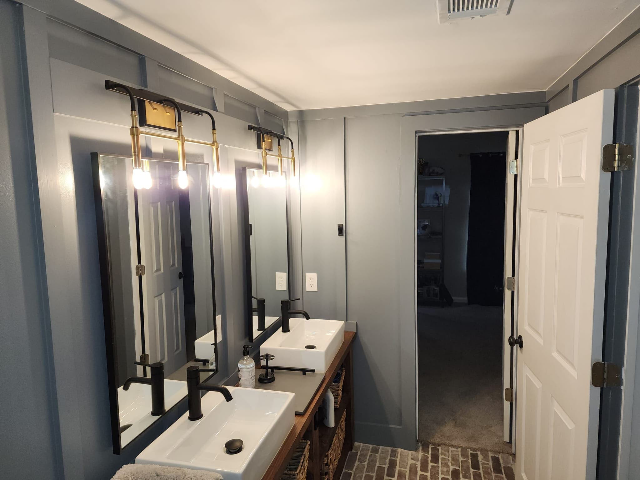 Double vanity with white vessel sinks, black faucets and Edison-bulb sconces