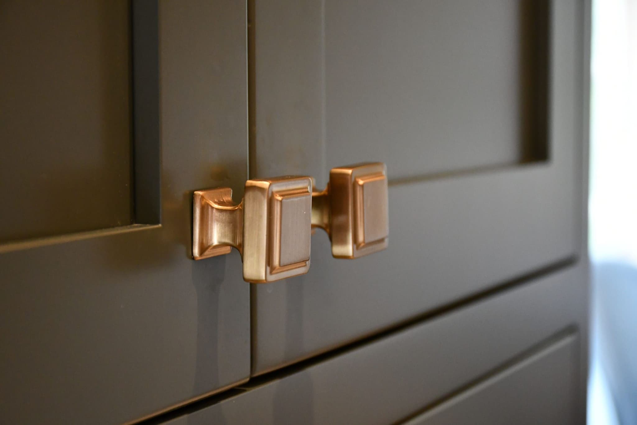 Close-up of brushed-gold cabinet hardware on olive cabinetry