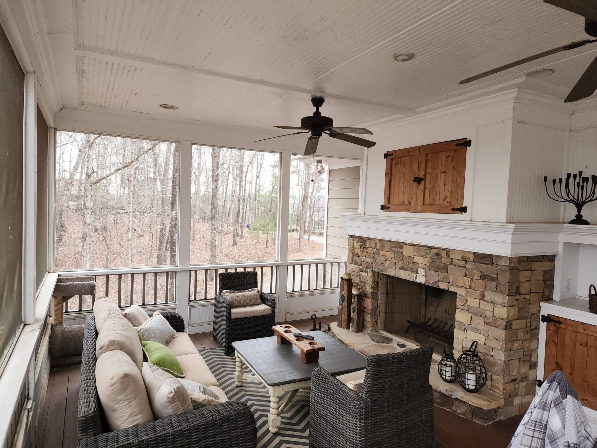 Wide screened porch with beadboard ceiling, fans and a stacked-stone fireplace