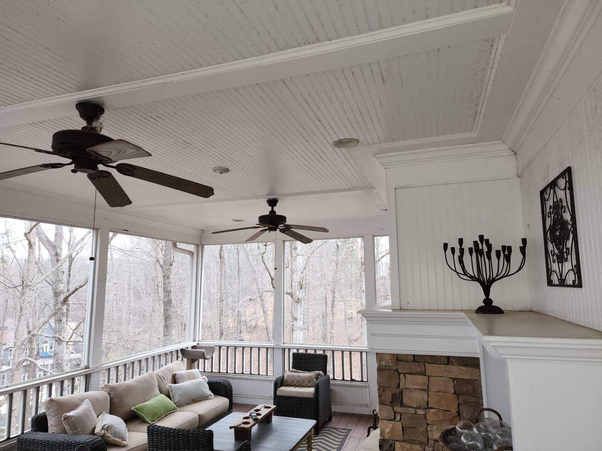 Screened porch with a stacked-stone wood-burning fireplace and wicker seating